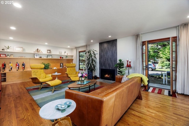 living room with recessed lighting, plenty of natural light, wood finished floors, and a fireplace