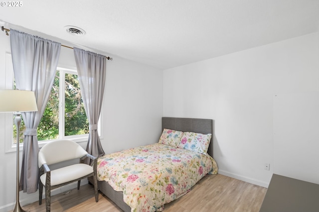 bedroom with wood finished floors, visible vents, and baseboards