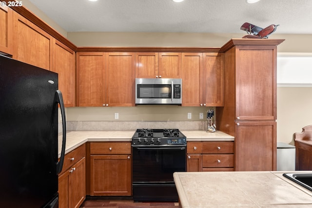 kitchen featuring black appliances, light countertops, and brown cabinetry