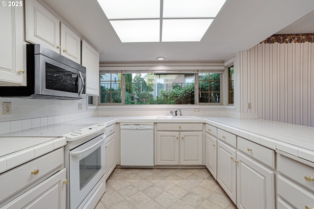7785 SW Fairway Dr, Wilsonville, OR 97070 - kitchen with white appliances, a sink, white cabinetry, tile counters, and light tile patterned floors