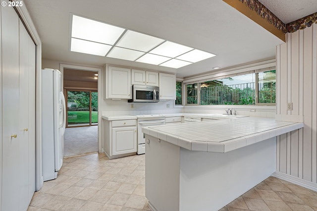 7785 SW Fairway Dr, Wilsonville, OR 97070 - kitchen featuring white appliances, a peninsula, white cabinets, and healthy amount of natural light