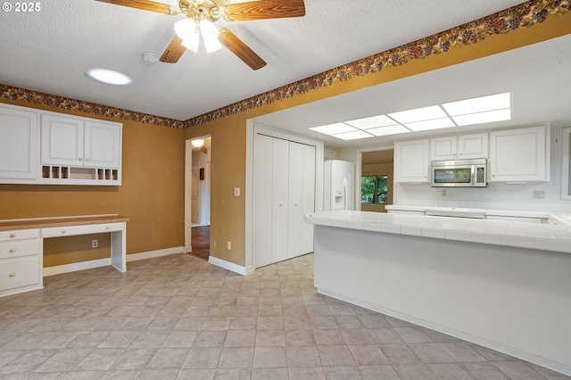 7785 SW Fairway Dr, Wilsonville, OR 97070 - kitchen with stainless steel microwave, tile countertops, white refrigerator with ice dispenser, a textured ceiling, and white cabinets