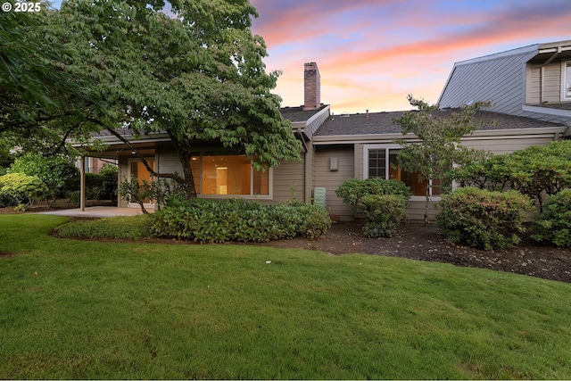 7785 SW Fairway Dr, Wilsonville, OR 97070 - back of property at dusk with a lawn and a chimney