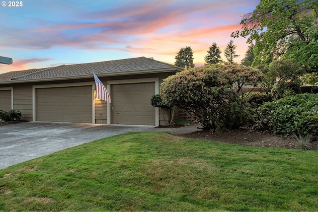 7785 SW Fairway Dr, Wilsonville, OR 97070 - garage at dusk featuring driveway and a lawn