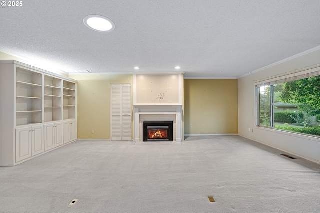 7785 SW Fairway Dr, Wilsonville, OR 97070 - unfurnished living room with a textured ceiling, crown molding, a fireplace with flush hearth, recessed lighting, and light colored carpet