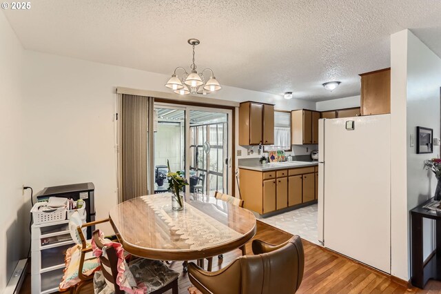 12330 SE Main St, Portland, OR 97233 - dining area with a chandelier, light wood-type flooring, a textured ceiling, and a baseboard heating unit