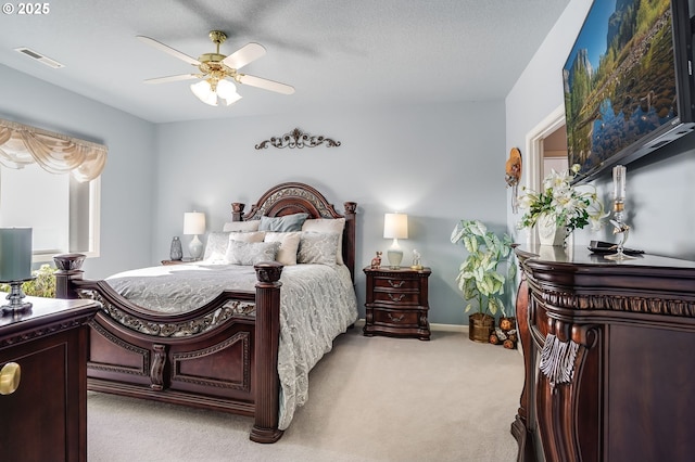 bedroom featuring light carpet, a textured ceiling, and ceiling fan