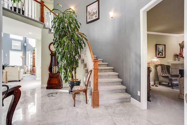 staircase with a high ceiling and ornamental molding