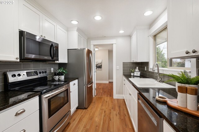 kitchen featuring white cabinets, backsplash, stainless steel appliances, and light hardwood / wood-style floors