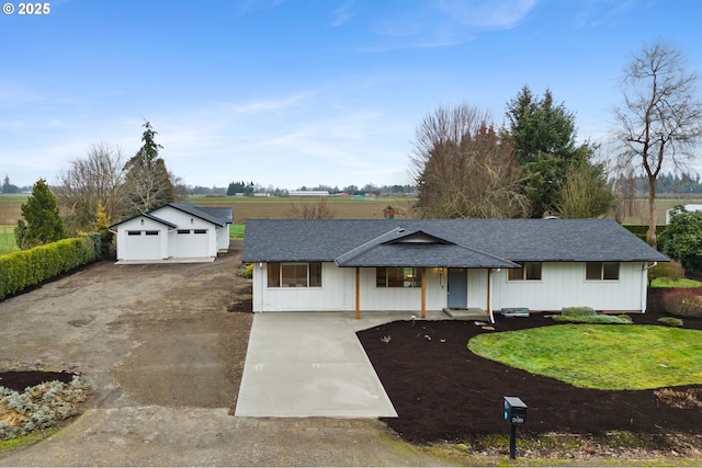 ranch-style home featuring a front yard, covered porch, a garage, and an outbuilding