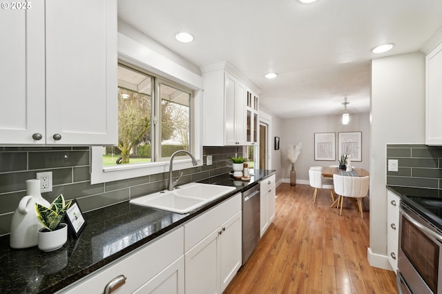 kitchen featuring white cabinets, appliances with stainless steel finishes, sink, backsplash, and light wood-type flooring