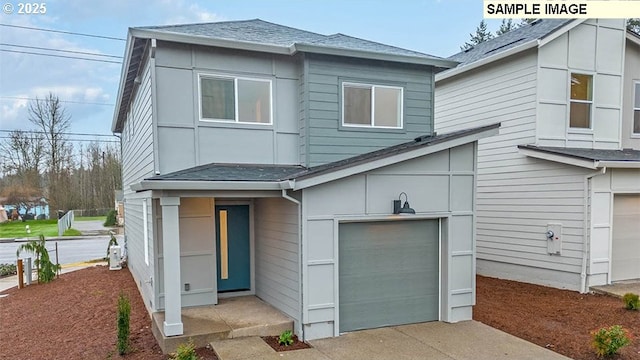 modern home with an attached garage, concrete driveway, a shingled roof, and a front yard