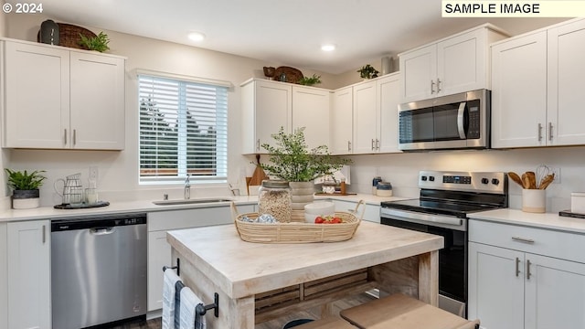 kitchen with stainless steel appliances, a sink, light countertops, and white cabinets