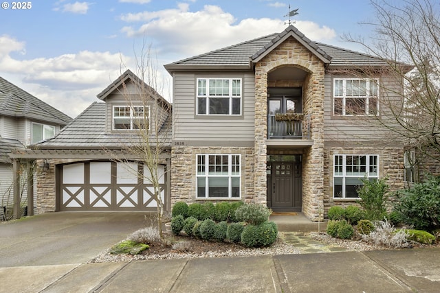 view of front of home with a garage, concrete driveway, and stone siding