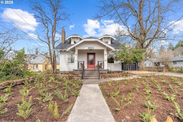 bungalow featuring a porch, a chimney, and fence