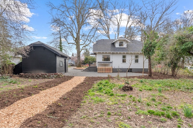 back of house with an outbuilding and dirt driveway