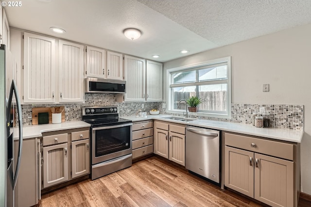14905 SE Stevenson Dr, Vancouver, WA 98683 - kitchen with stainless steel appliances, a sink, a textured ceiling, tasteful backsplash, and light wood finished floors
