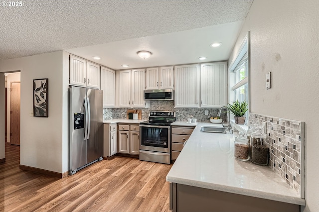 14905 SE Stevenson Dr, Vancouver, WA 98683 - kitchen featuring stainless steel appliances, a sink, decorative backsplash, light wood-type flooring, and a textured ceiling