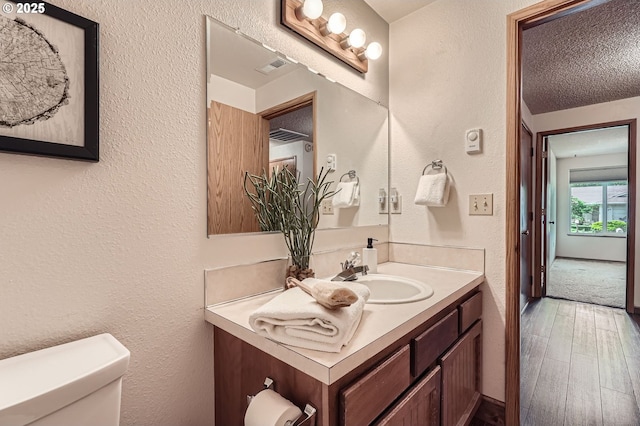 14905 SE Stevenson Dr, Vancouver, WA 98683 - half bathroom with vanity, toilet, wood finished floors, a textured wall, and a textured ceiling
