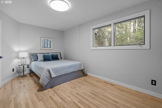 bedroom featuring light wood-type flooring, visible vents, and baseboards