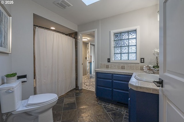 bathroom featuring visible vents, a shower with shower curtain, toilet, stone finish floor, and vanity