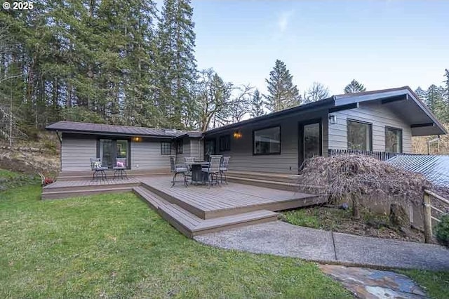 rear view of property featuring a yard and a deck