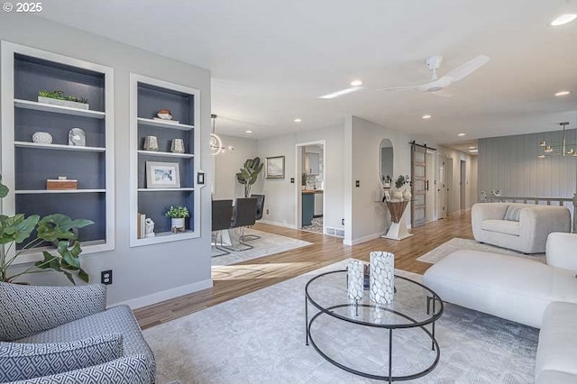 living area featuring built in shelves, wood finished floors, and recessed lighting