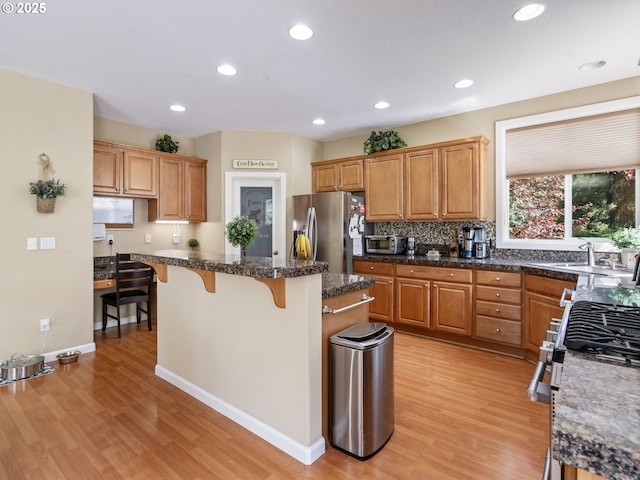 22824 NE 254th Ct, Battle Ground, WA 98604 - kitchen with appliances with stainless steel finishes, light wood-style flooring, a kitchen bar, a kitchen island, and recessed lighting