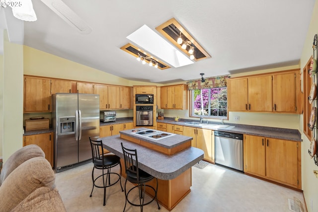 kitchen with stainless steel appliances, a breakfast bar, vaulted ceiling, a center island, and dark countertops