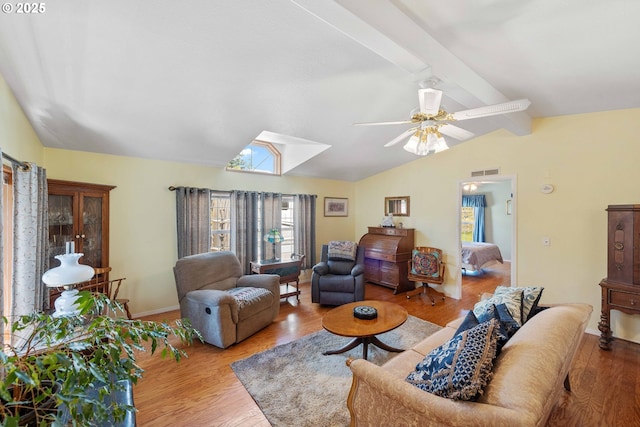 living area with ceiling fan, visible vents, vaulted ceiling with beams, and wood finished floors