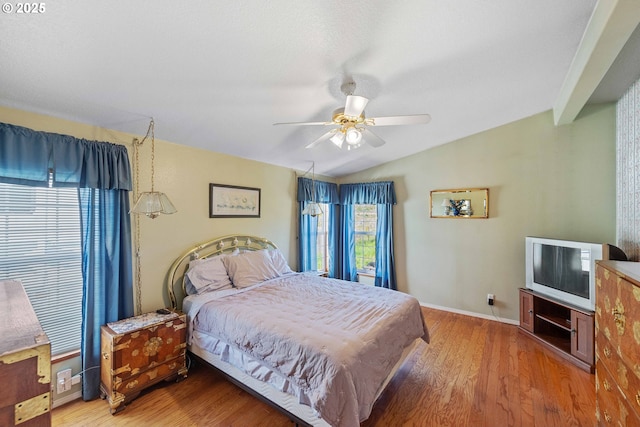 bedroom featuring lofted ceiling, baseboards, light wood-type flooring, and a ceiling fan