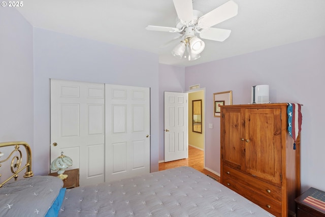 bedroom featuring a closet, wood finished floors, visible vents, ceiling fan, and baseboards