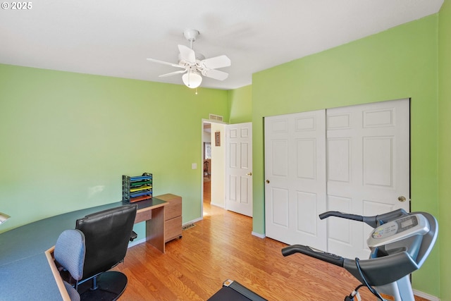 office featuring baseboards, a ceiling fan, visible vents, and light wood-style floors