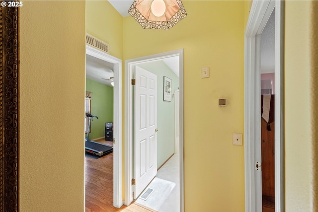 hall featuring light wood-type flooring and visible vents
