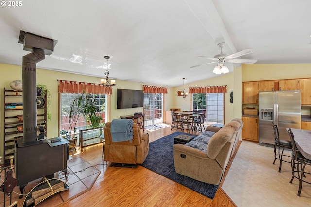 living room featuring lofted ceiling with beams, light wood-style flooring, and ceiling fan with notable chandelier
