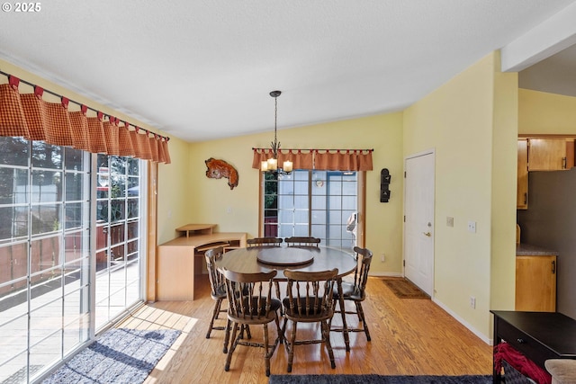 dining space with lofted ceiling, baseboards, light wood finished floors, and a chandelier