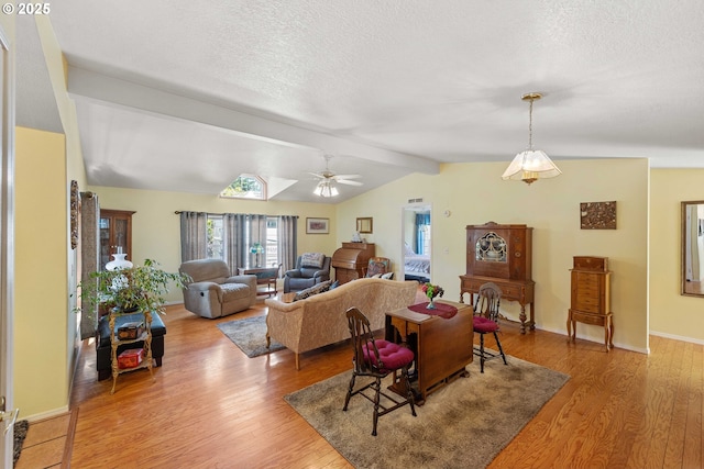 dining room with a textured ceiling, light wood-style flooring, and lofted ceiling with beams