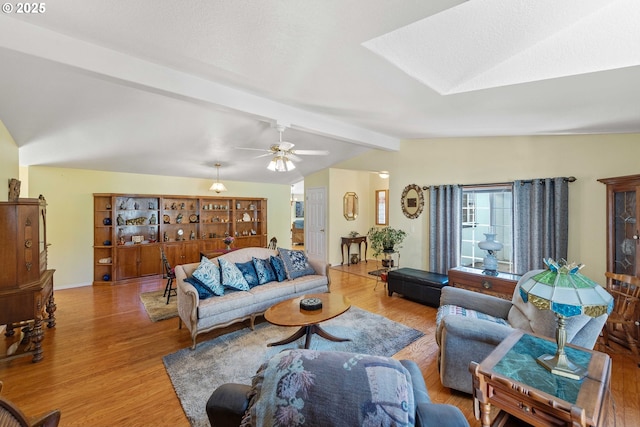 living area featuring ceiling fan, vaulted ceiling with beams, and wood finished floors