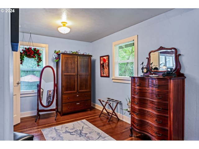bedroom with baseboards, dark wood finished floors, and multiple windows