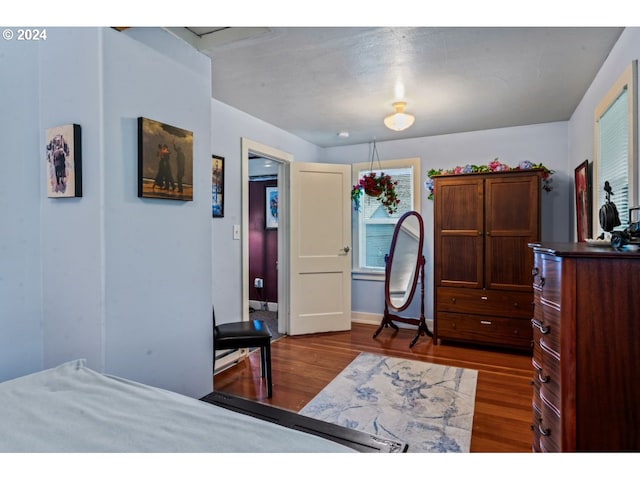 bedroom with dark wood-style flooring and baseboards