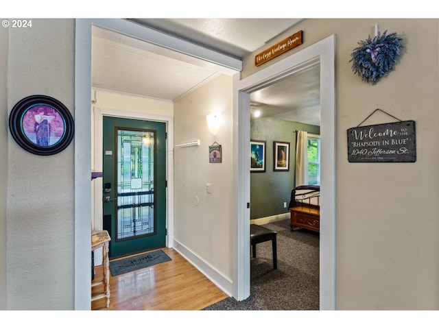 foyer featuring carpet flooring, baseboards, and wood finished floors