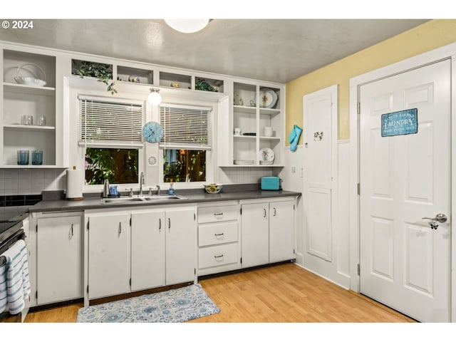 kitchen featuring a sink, dark countertops, open shelves, and light wood-style flooring