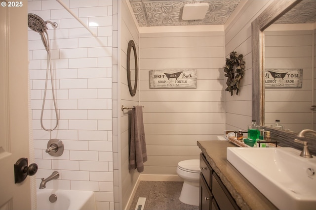 full bathroom with toilet, vanity, wood walls, and tiled shower / bath combo