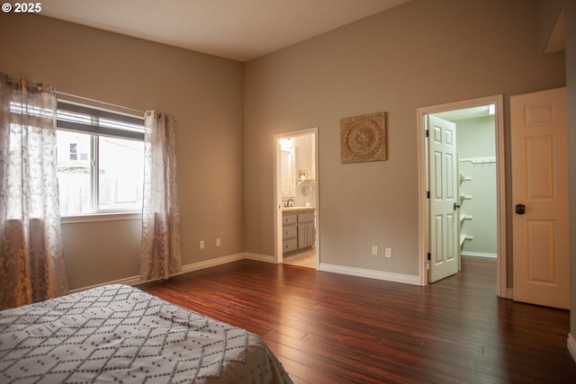 unfurnished bedroom featuring sink, a spacious closet, connected bathroom, a closet, and dark hardwood / wood-style flooring