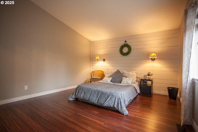 bedroom featuring vaulted ceiling, wood walls, and dark hardwood / wood-style floors