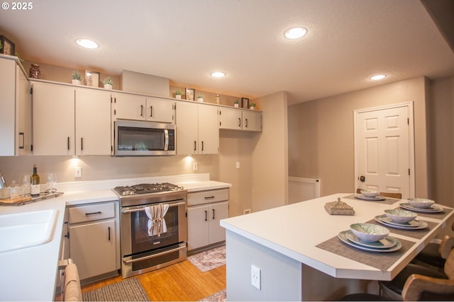 kitchen featuring white cabinets, stainless steel appliances, light hardwood / wood-style flooring, and sink