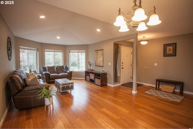 living room with lofted ceiling, a chandelier, and hardwood / wood-style flooring