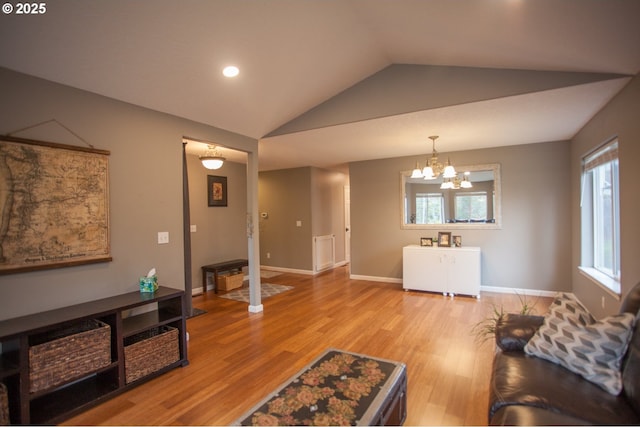 living room featuring light hardwood / wood-style floors, an inviting chandelier, and vaulted ceiling