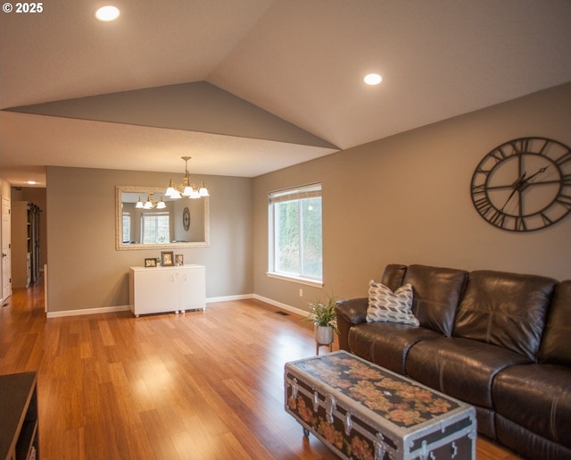 living room with lofted ceiling, an inviting chandelier, and hardwood / wood-style floors