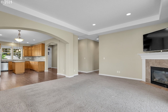 20021 Tharp Ct, Oregon City, OR 97045 - unfurnished living room featuring dark colored carpet, recessed lighting, arched walkways, a tiled fireplace, and a tray ceiling